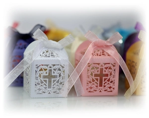 Close-up of laser-cut cross patterns on white and pink hollow wedding candy boxes