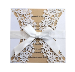 Detail of laser-cut snowflake invitation sleeve with brown card and white silk ribbon bow