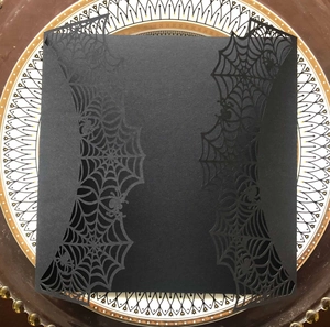 Detail of laser-cut spider web pattern on a matte black Halloween invitation card