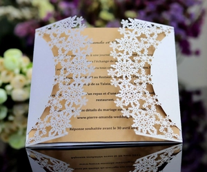 Detail of laser-cut white snowflake wedding invitation with elegant gold inner card