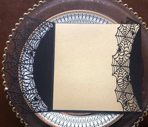 Laser cut spider web Halloween invitation card with kraft paper insert on a glass tray