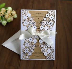 Détail d'invitation découpée au laser avec insert en kraft et nœud de ruban en soie