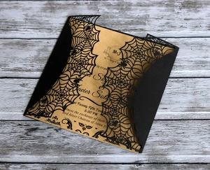 Macro shot of laser-cut black spider web cover and kraft paper Halloween wedding invite