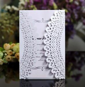 Detail of laser-cut white wedding invitation with elegant floral patterns and purple insert card