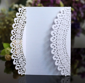 Close-up of laser-cut lace floral pattern on elegant white wedding invitation cover