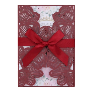 Elegant laser-cut burgundy wedding invitation with white floral card and red silk bow