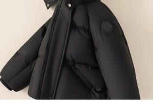 Detail of waterproof black kids' down jacket with leather logo patch and silver snaps