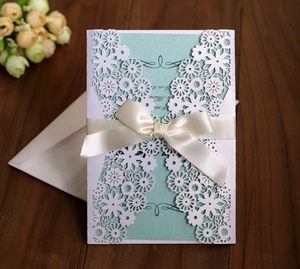 Faire-part de mariage blanc découpé au laser avec insert vert menthe et nœud en satin