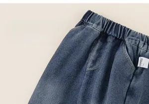 Detail of dark blue denim jeans showing elastic waistband and stitching on children's pants