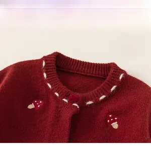 Detail of red knitted cardigan featuring a classic round neck and mushroom embroidery