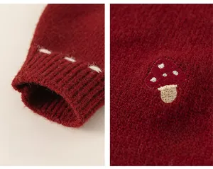 Detail of red knit sweater featuring mushroom embroidery and ribbed cuffs for kids