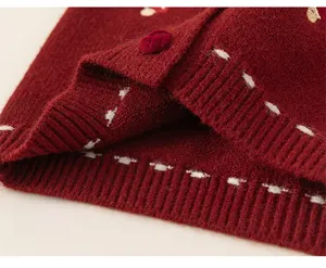 Macro detail of burgundy knit cardigan hem with ribbed texture and white contrast stitching