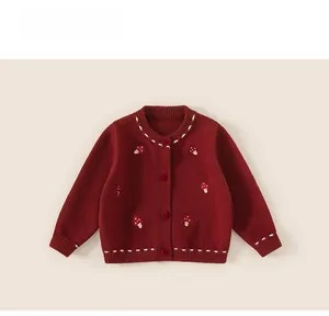 Close-up of baby winter cardigan with red buttons and embroidered mushroom patterns