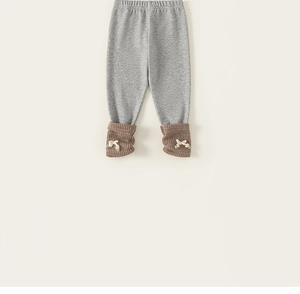 Detail of light grey knitted toddler leggings with brown ribbed cuffs and white bows