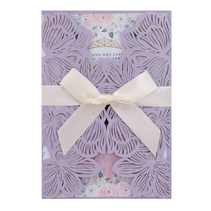 Elegant lavender laser-cut wedding invitation with a white satin ribbon bow and floral insert