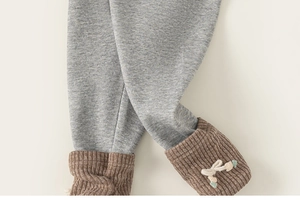 Detail of grey knitted toddler leggings featuring brown ribbed cuffs and a cute bow