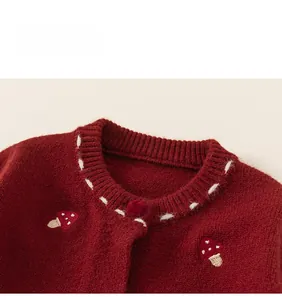 Close-up of red knit cardigan with embroidered mushrooms and ribbed round collar details