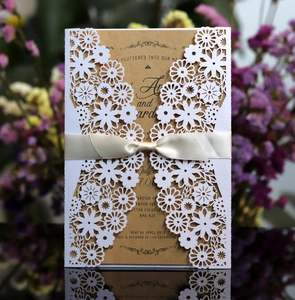 Détail du faire-part de mariage découpé au laser avec papier perlé et nœud en satin