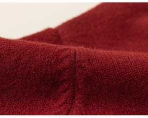 Close-up of deep red knitted fabric showing thick texture and neat stitching details