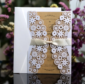 Détail d'un faire-part de mariage ajouré au laser avec motif floral et papier kraft