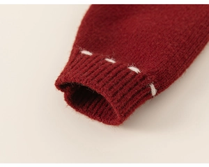 Detailed close-up of red knitted cardigan sleeve with ribbed cuff and white decorative stitching