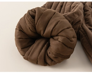Detailed close-up of dark brown corduroy fabric with thick quilted warm lining