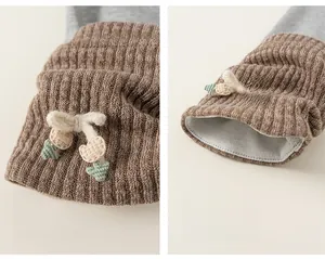Detailed close-up of ribbed knit cuffs with 3D knitted bows and green leaf accents