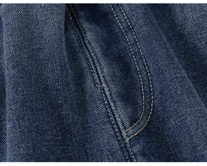 Macro view of deep blue denim fabric with orange double-stitching and twill texture