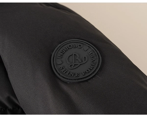 Detail of waterproof black down jacket with rubber brand patch on the sleeve