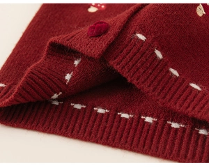 Close-up of red festive knit cardigan showing white stitching and mushroom embroidery detail
