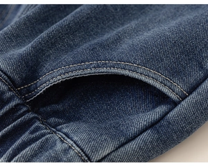 Detail of dark blue denim pants showing elastic waist and durable stitching textures