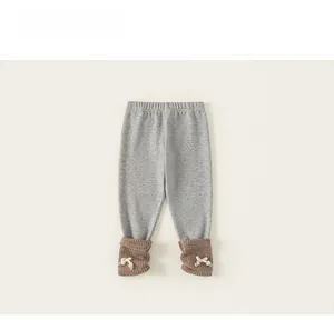 Detail of grey knitted toddler leggings featuring brown ribbed cuffs and white bows