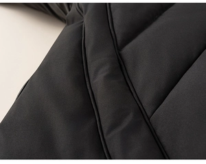 Close-up of matte black quilted fabric and thick insulation on hooded winter puffer jacket