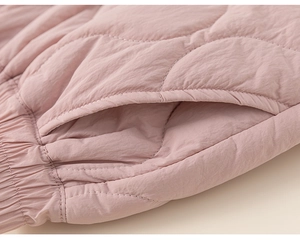 Close-up detail of pink quilted children trousers showing wavy stitching and pocket