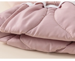 Close-up of pink quilted fabric detailing stitching and texture for kids winter pants