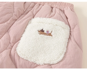 Detail view of pink quilted fabric with white lamb wool pocket and dog embroidery on trousers