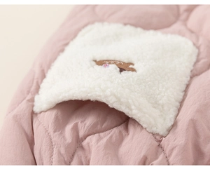 Detail of pink quilted fabric with white sherpa patch and brown bear embroidery