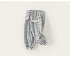 Détail macro du pantalon gris pour enfant avec bordure en dentelle et broderie florale