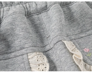 Détail du pantalon en tricot gris pour enfant avec taille élastique et broderie florale