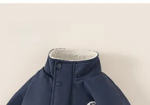 Close-up of kids navy jacket collar featuring soft white fleece lining and embroidered patch
