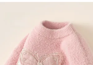Close-up of pink fluffy knit sweater showing sequined butterfly and soft plush texture