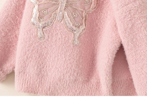 Close-up of pink plush knit sweater featuring detailed butterfly sequin and bead embroidery