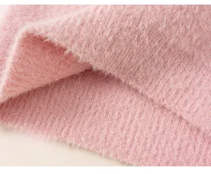 Detailed shot of pink plush knit sweater fabric showing soft texture and loose hem detail