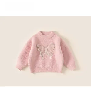 Close-up of girls' fuzzy pink sweater featuring detailed bow embroidery and soft texture