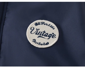 Detail shot of navy blue kids jacket featuring an embroidered vintage badge on the fabric