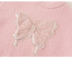 Close-up of pink fluffy sweater with sequined mesh butterfly and pearl details