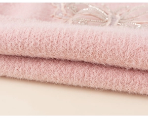Close-up of pink knit fabric featuring fuzzy texture and silver sequin butterfly embroidery