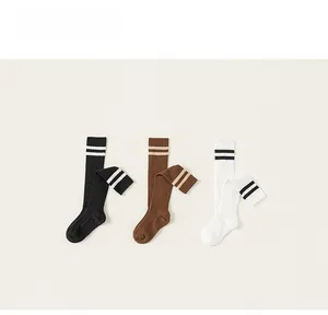 Close-up of three pairs of ribbed cotton knee-high socks in black, brown and white colors