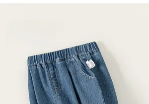Dettaglio dei jeans blu scuro con elastico in vita e accenti di fiocchi ricamati per bambine