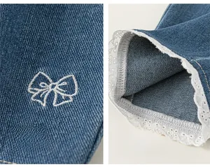Dettaglio del ricamo a fiocco bianco e dell'orlo in pizzo su questi jeans da bambina